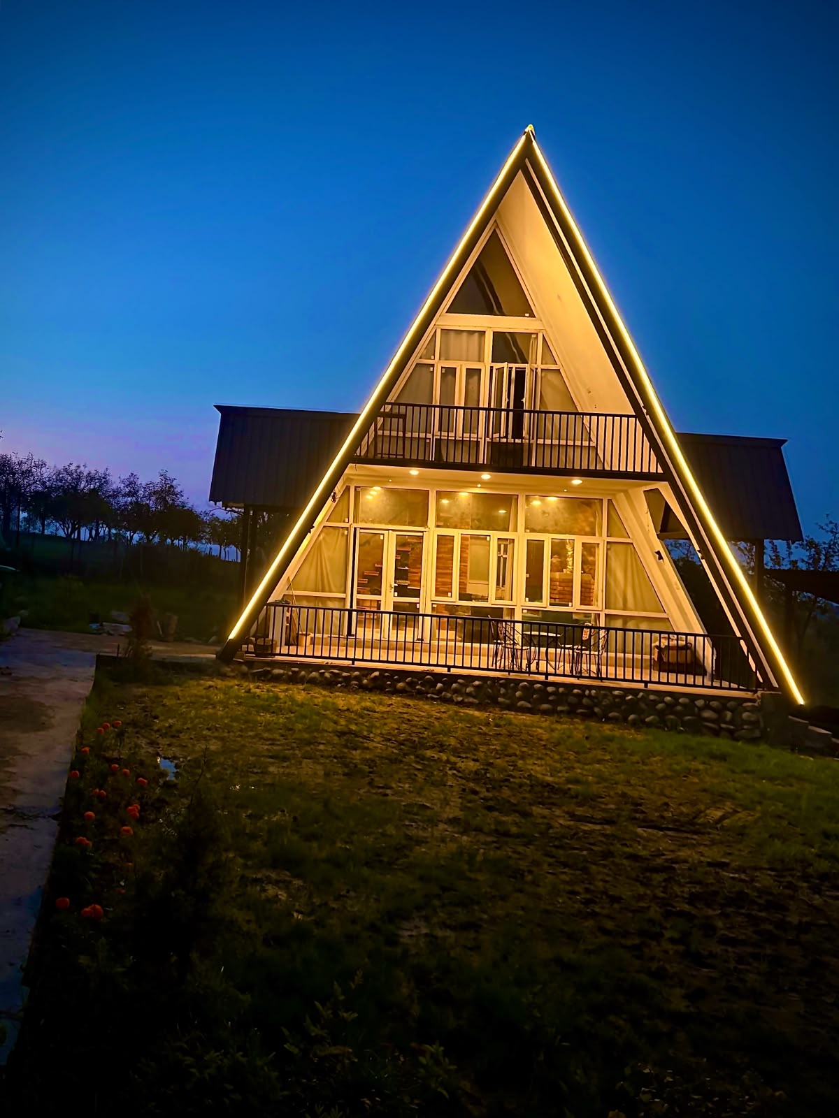 Raiyar Resort A-frame cottage glowing at twilight in Doodhpathri